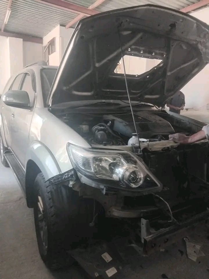 Silver SUV undergoing repair with its hood raised in a workshop